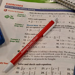 Red Pembroke Public Library pen resting on page of open math textbook.