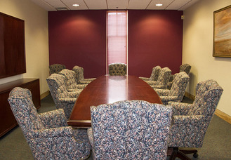Photo of Trustees Meeting Room. A table runs the lnegth of the room.  10 padded chairs are arranged around it. Two extra chairs sit in the corners.