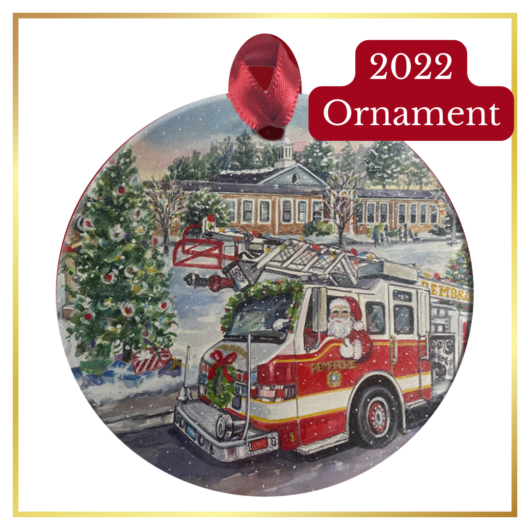 A round ornament with a painting of Santa Claus driving a Pembroke fire truck in front of Christmas trees and the old Pembroke Rec Center.
