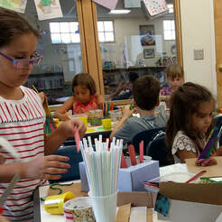 Elementary-age children work at various tables with craft items.