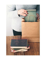Image of person placing book in brown bag