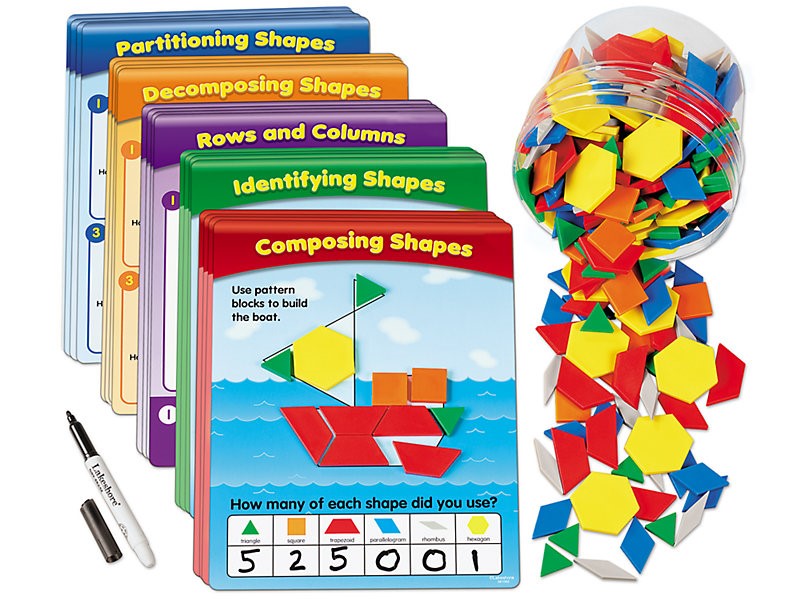 ID: Pattern blocks spilling out of clear container. To the left of this are groups of Pattern Block activity cards are stacked into 5 groups; the following groups are listed on the top of each pile: Composing Shapes, Identifying Shapes, Rows & Columns, Decomposing Shapes, Partitioning Shapes.